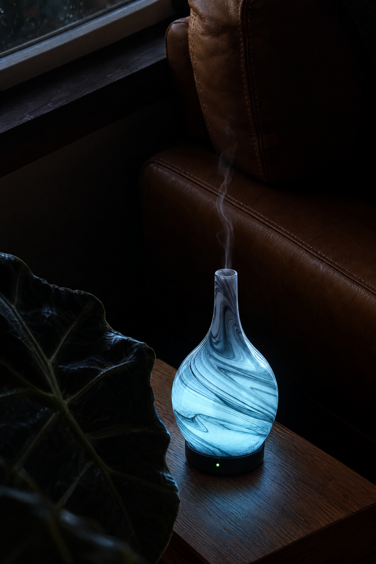 Nebula marbled glass diffuser glowing pale blue beside a leather armchair