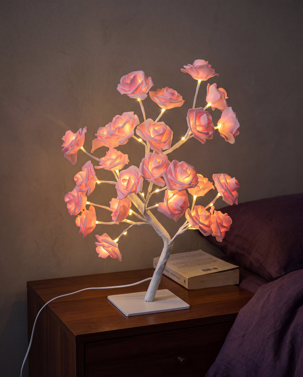 Pink Floreo rose tree lamp lit on a bedside table