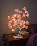 Pink Floreo rose tree lamp lit on a bedside table