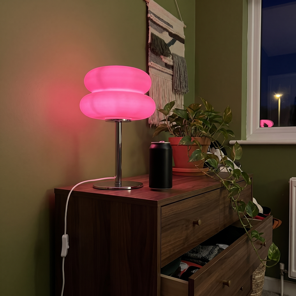 Pink Cumulus table lamp glowing on a walnut chest of drawers
