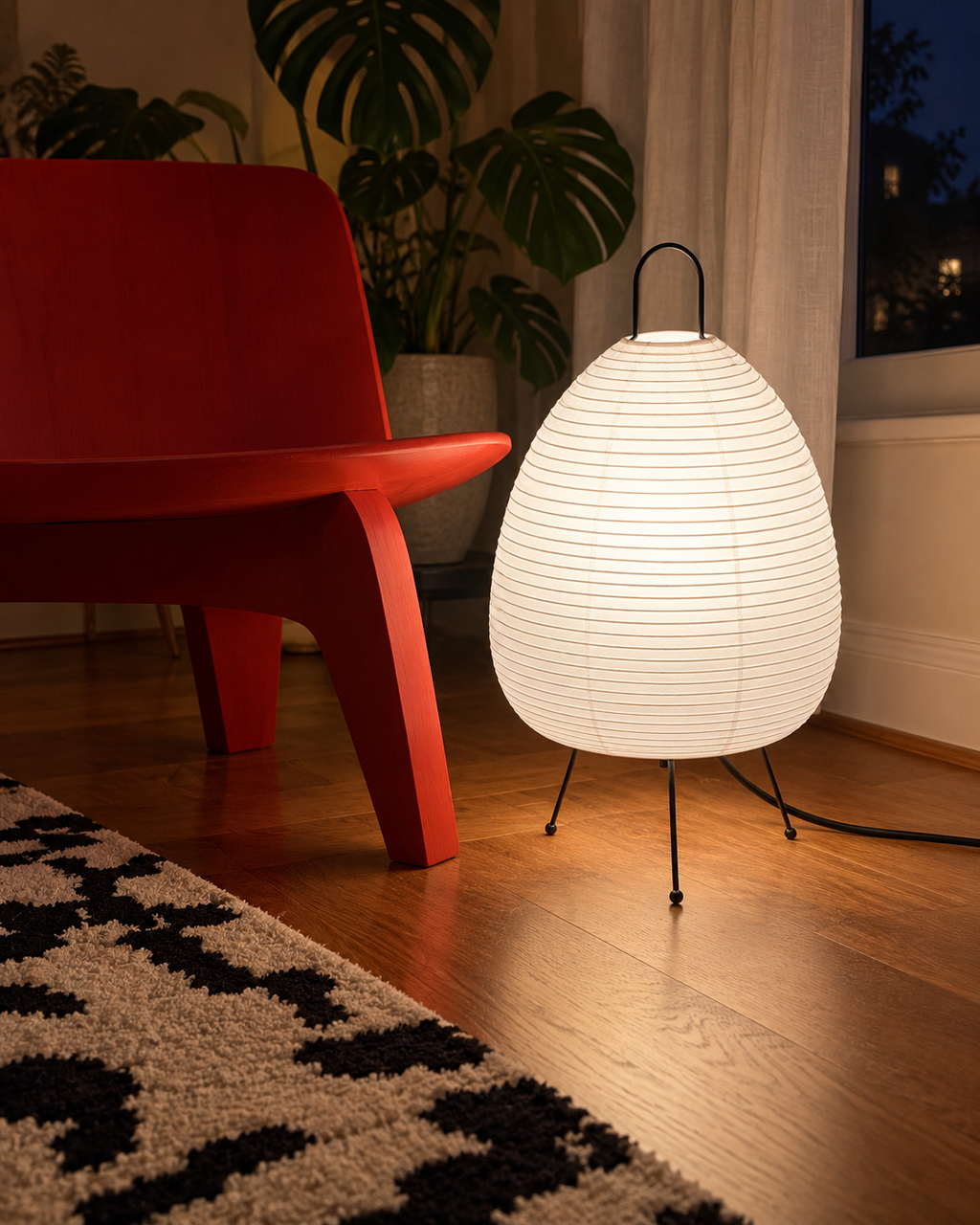 Charta in white light beside a red chair, showing its full tripod form