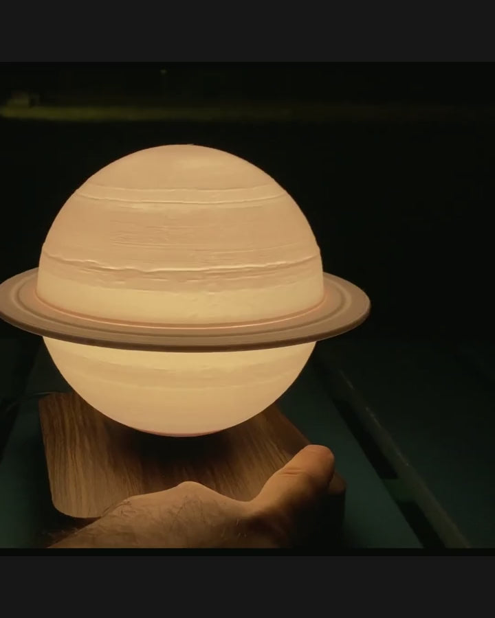 Sidera Saturn lamp floating above its base — muted demonstration