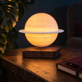 Sidera levitating Saturn lamp with a pale ring and glowing peach globe above a wood-effect base