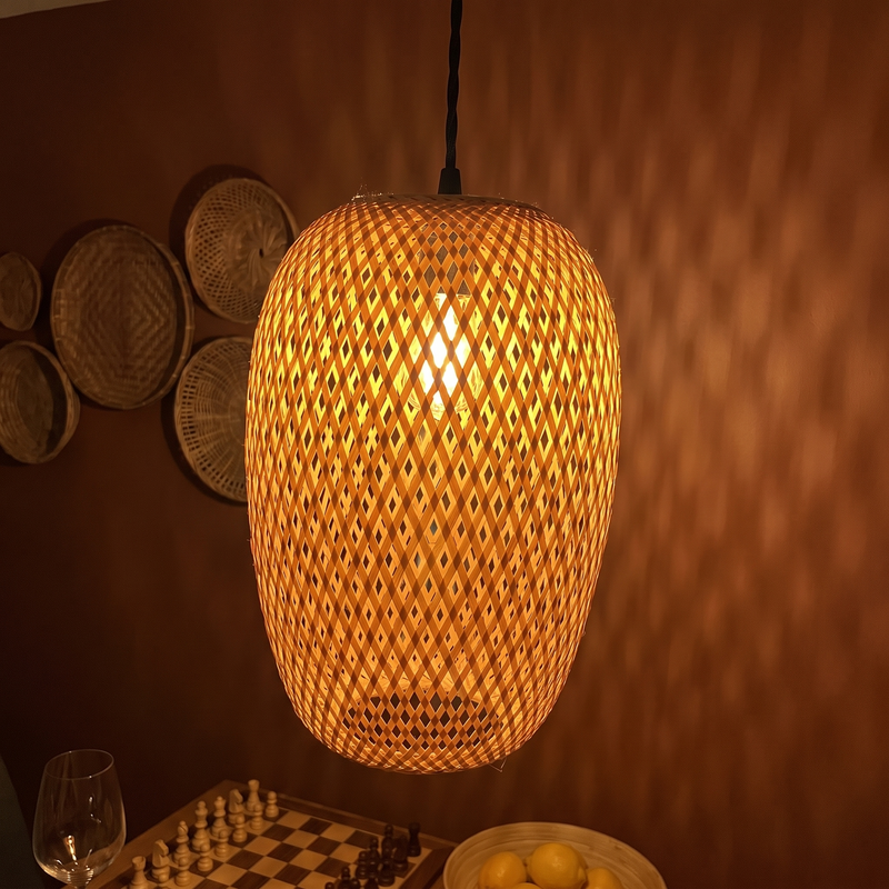 Tessera woven bamboo pendant lit over a dining table at night